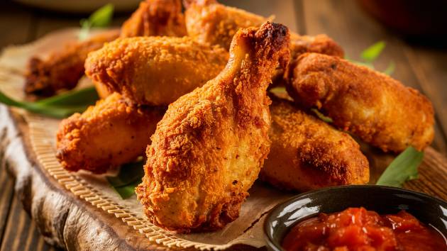 Coxinhas de frango douradas e crocantes recém-feitas na Air Fryer, servidas em uma tábua de madeira com molho de tomate ao lado.
