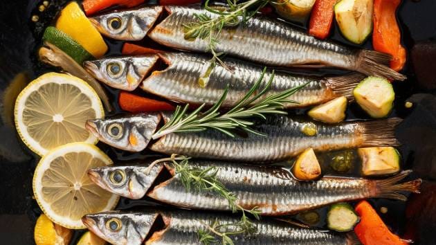 Sardinhas ao forno com ervas frescas e rodelas de limão.