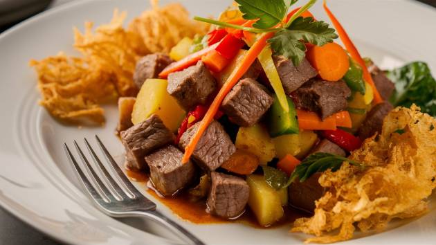 Prato de picadinho de carne com legumes e farofa.